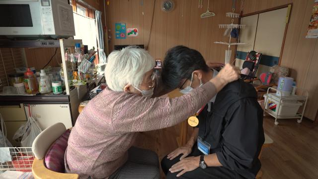 大塚さんの首に金メダルをかける小森さん