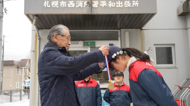 長原庵里さんの首に金メダルをかける前鼻 守さん