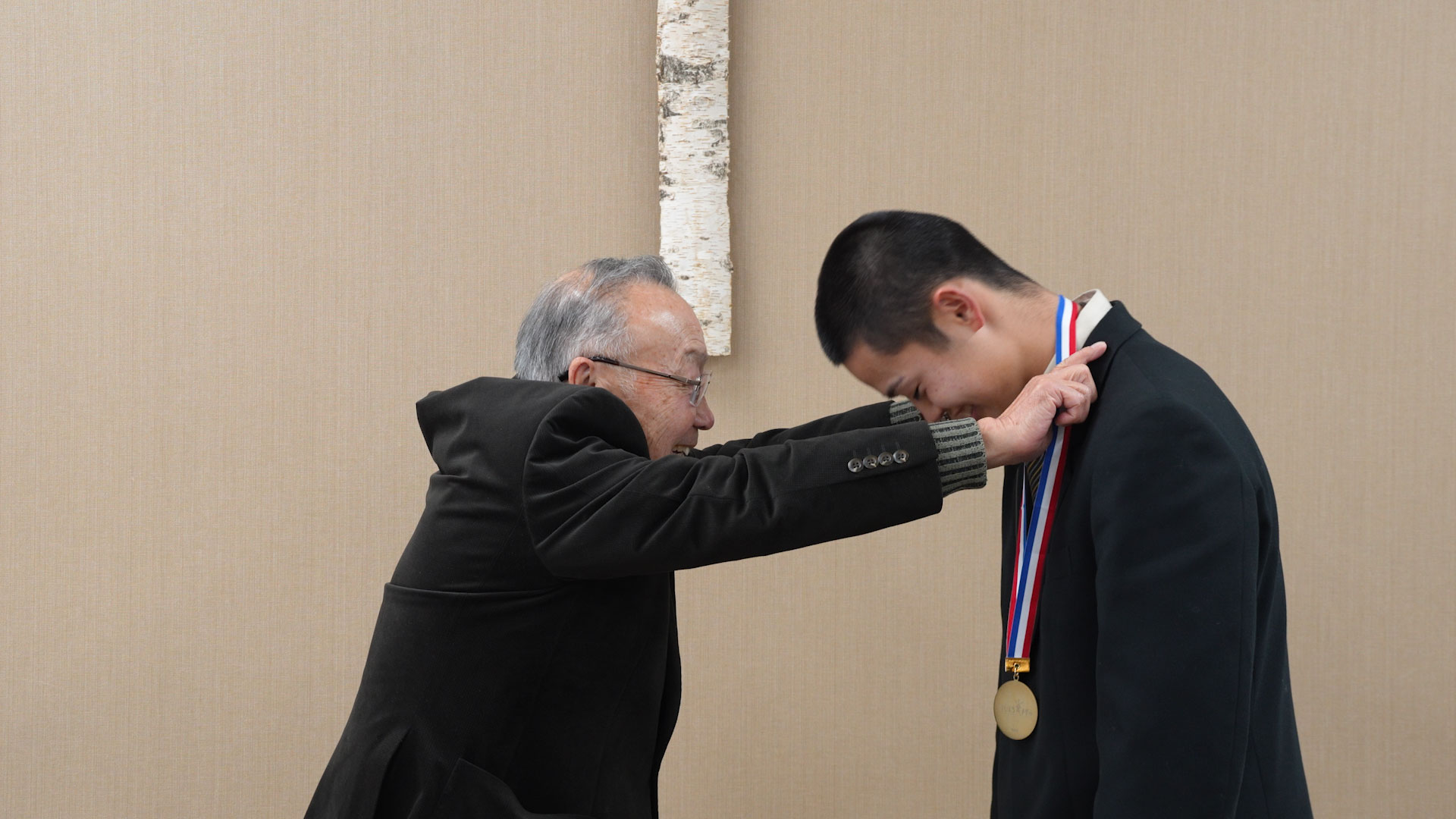 厚別東町内会連合会 会長の菊地邦夫さんから金メダルを贈られる向井悠真さん