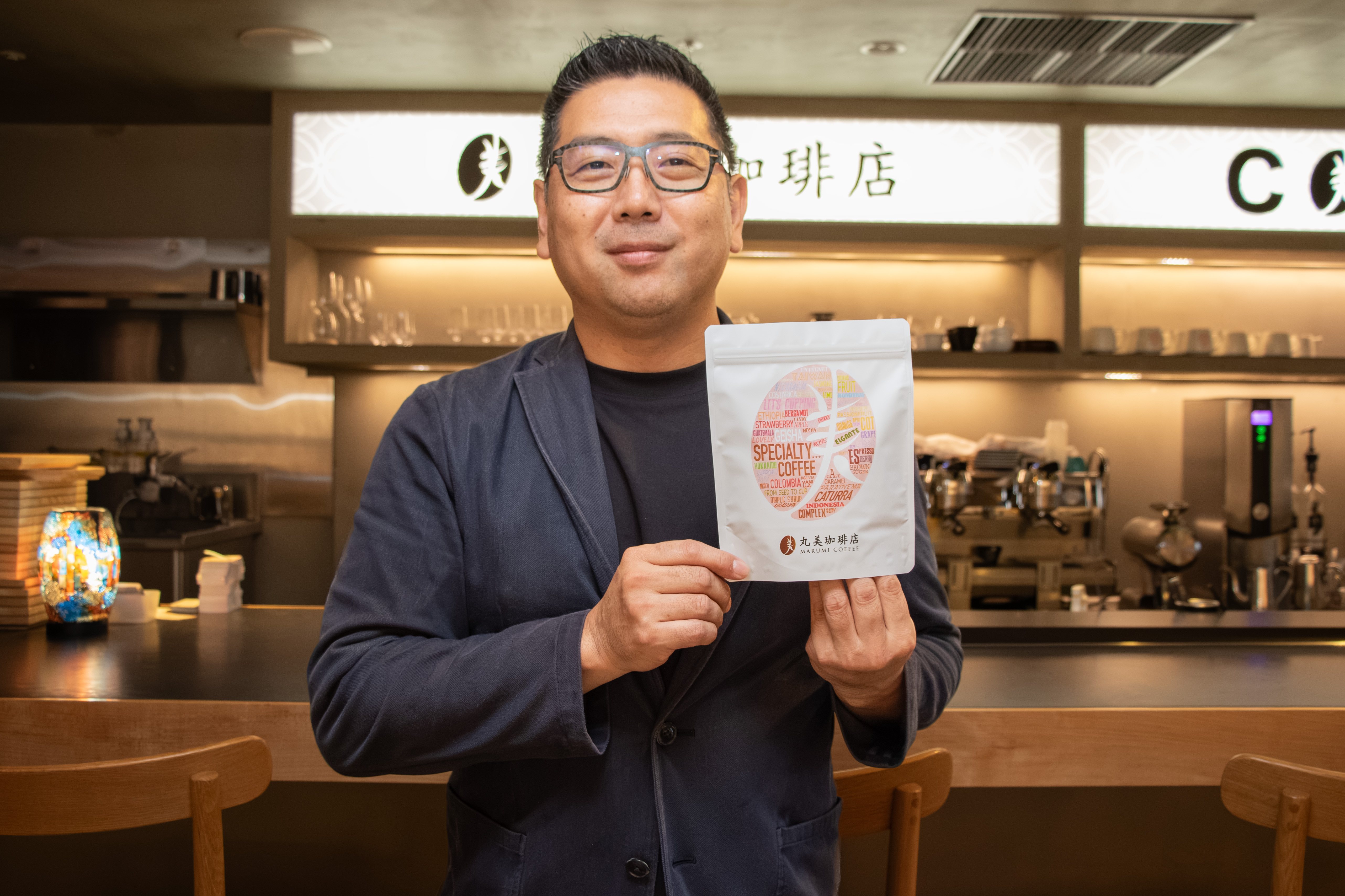 札幌の丸美珈琲店でスペシャルティコーヒーのパッケージを手にする後藤栄二郎さん